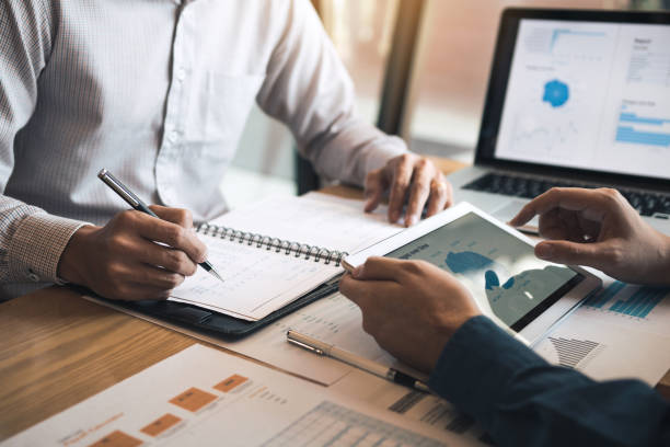 istockphoto-1183666141-612x612 Two business partnership coworkers discussing a financial planning graph and company during a budget meeting in office room.